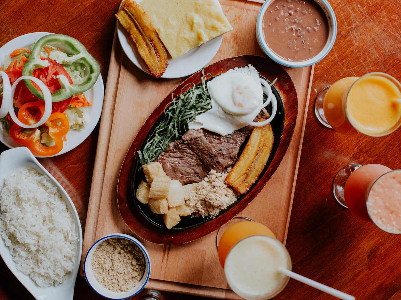 Almuerzo casero colombiano servido en la mesa: arroz, ensalada, sopa, maduro y jugo